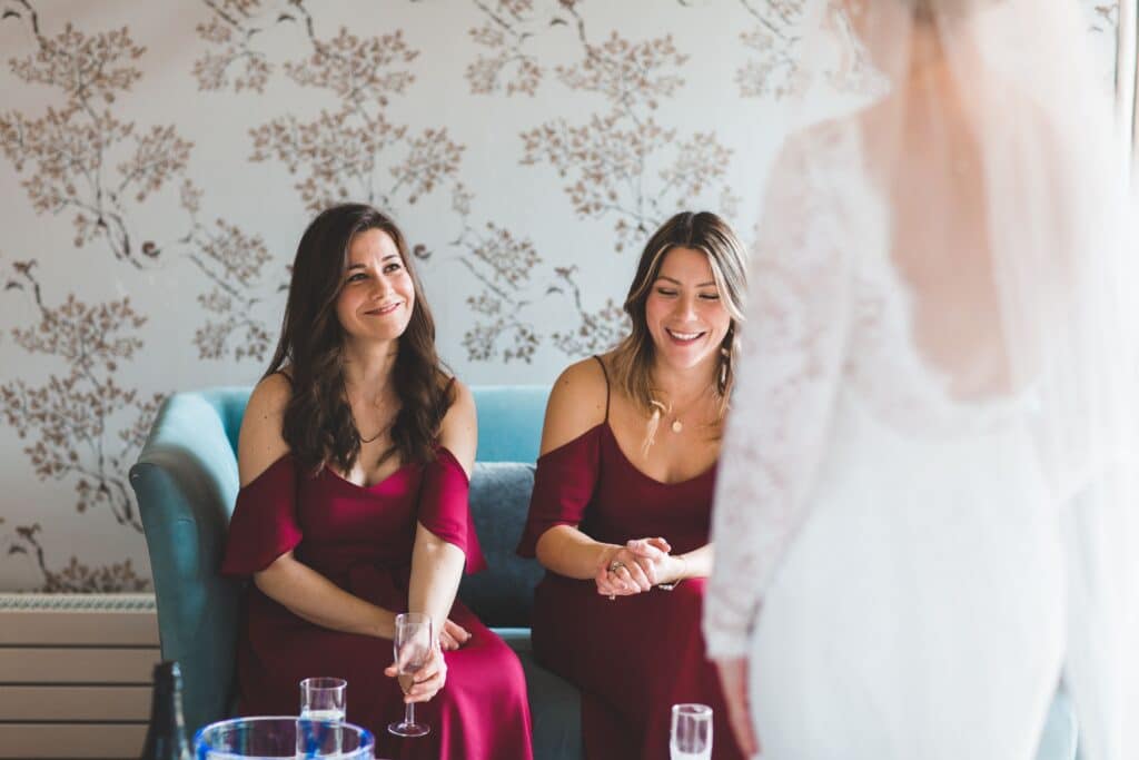 Bridesmaids see bride for first time in luxury suite at wedding venue