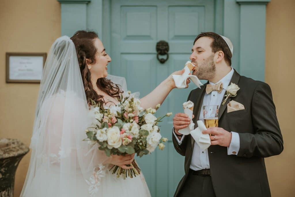 Bride and Groom share ice cream in front of blue door at country house wedding venue 