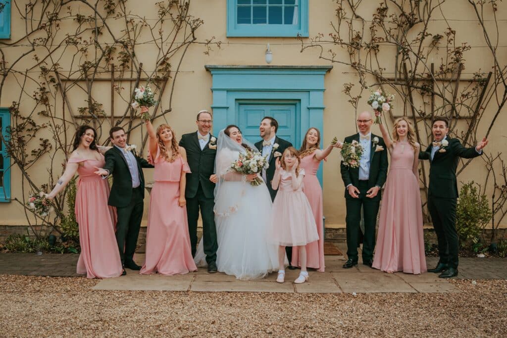 Bride and Groom at Jewish wedding in front on country farmhouse with their bridesmaids and groomsmen 