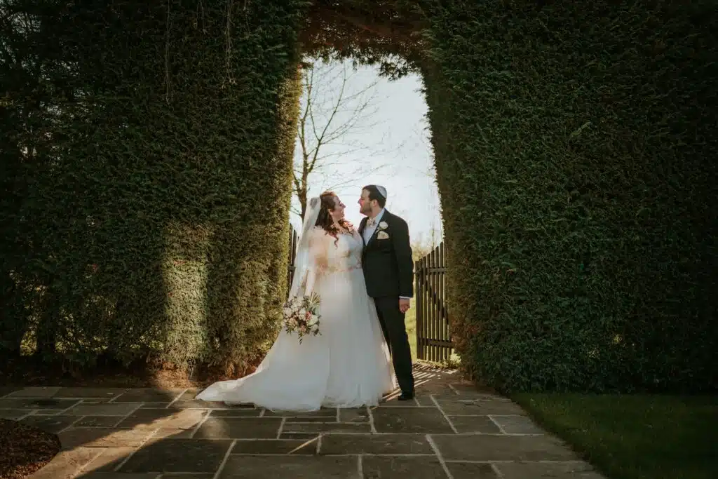 Bride and Groom on their wedding day celebrating their Jewish wedding in garden setting 