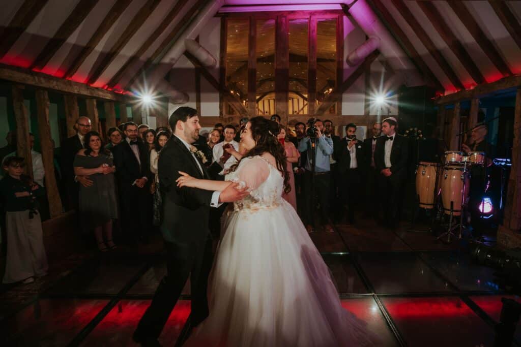 Bride & Groom at Jewish Wedding in barn venue start their first dance in front of their wedding guests 