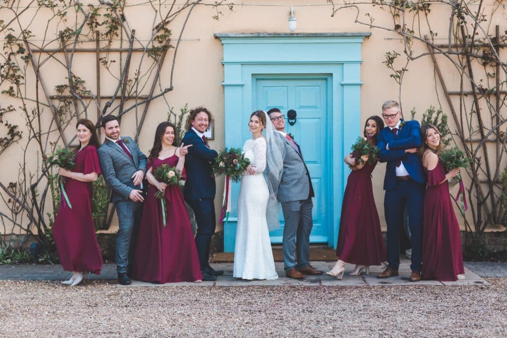 Bride groom and bridal party pose for photo in front of county farm house wedding venue