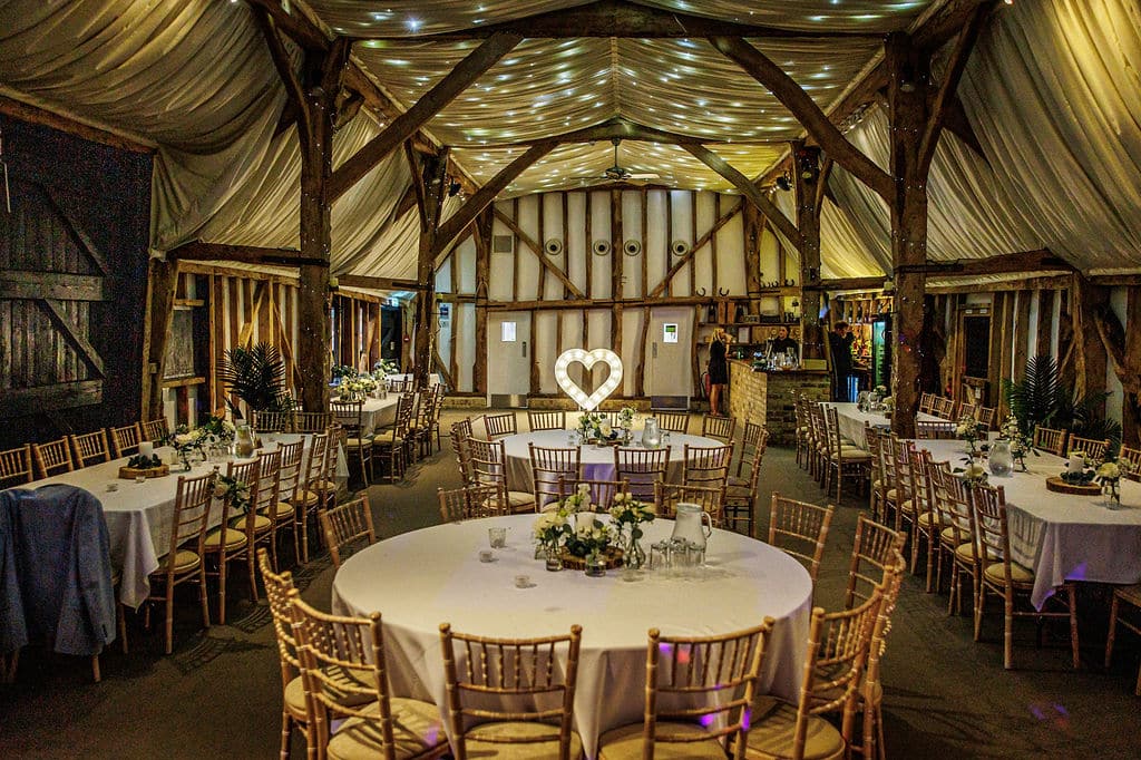 Barn wedding venue lit up with twinkly fairy lets and set for wedding reception
