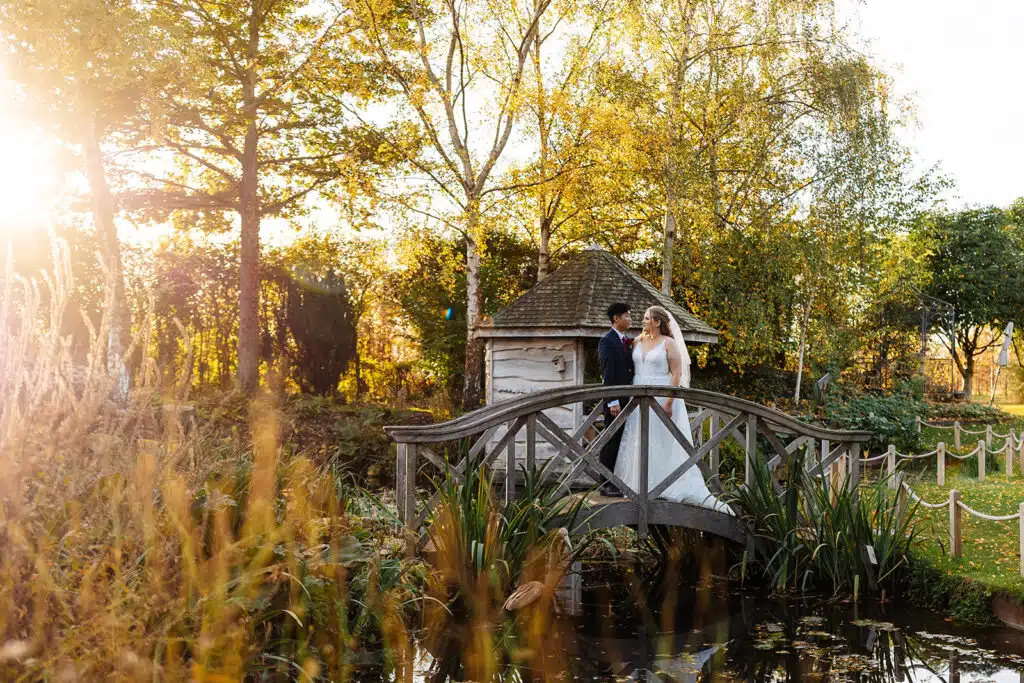 Autumn wedding couple on bridge in garden on wedding day