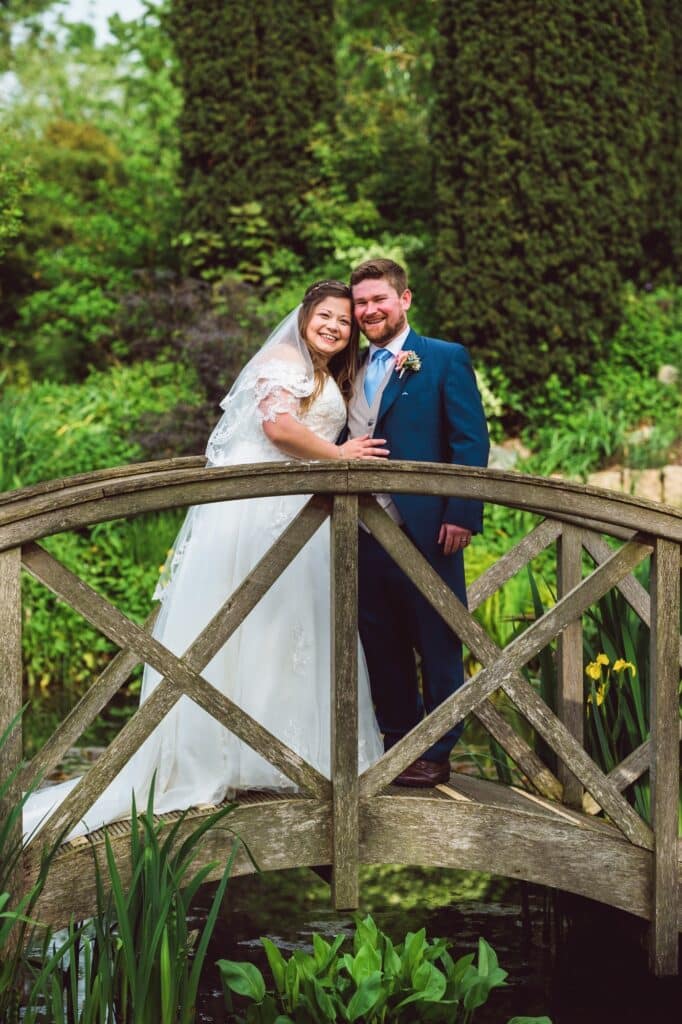Bride and groom on garden bridge at outdoor wedding venue 