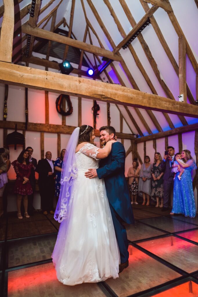 Bride and groom enjoy first dance on wedding day in rustic barn with mood lighting 