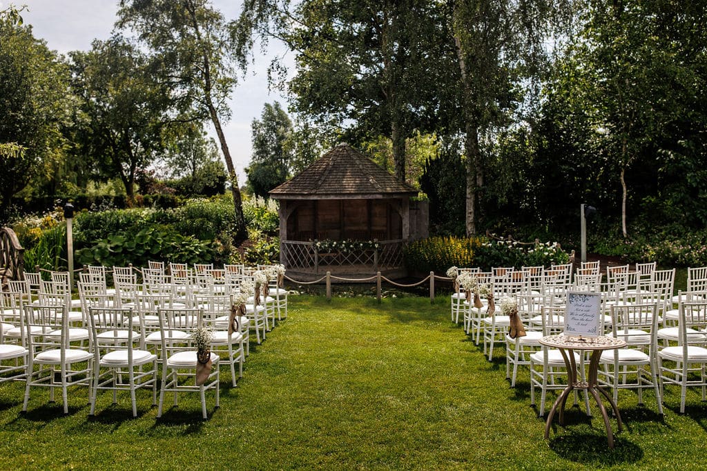 Garden set with white ceremony chairs and aisle ready for wedding
