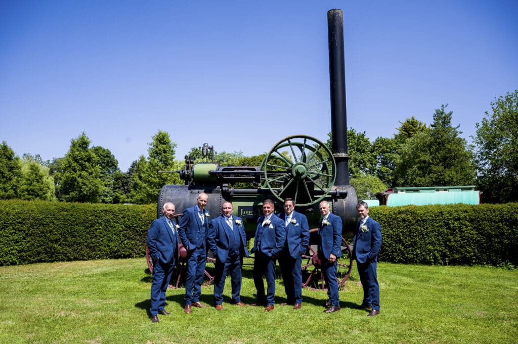 Groom and Groomsmen on summer wedding day in front of vintage steam engine 