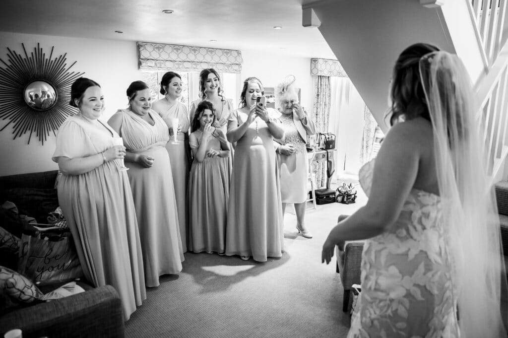 Black and white photo of bridesmaid in luxury wedding suite having first glimpse of bride on wedding day
