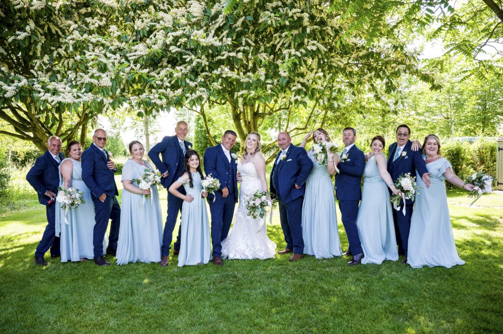 Bride and groom on their wedding day with bridesmaids and groomsmen in gardens of countryside wedding venue