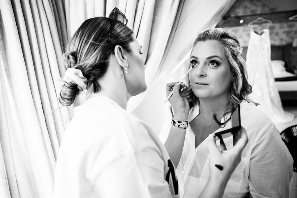 Make up artist puts finishing touches to brides making on wedding day 