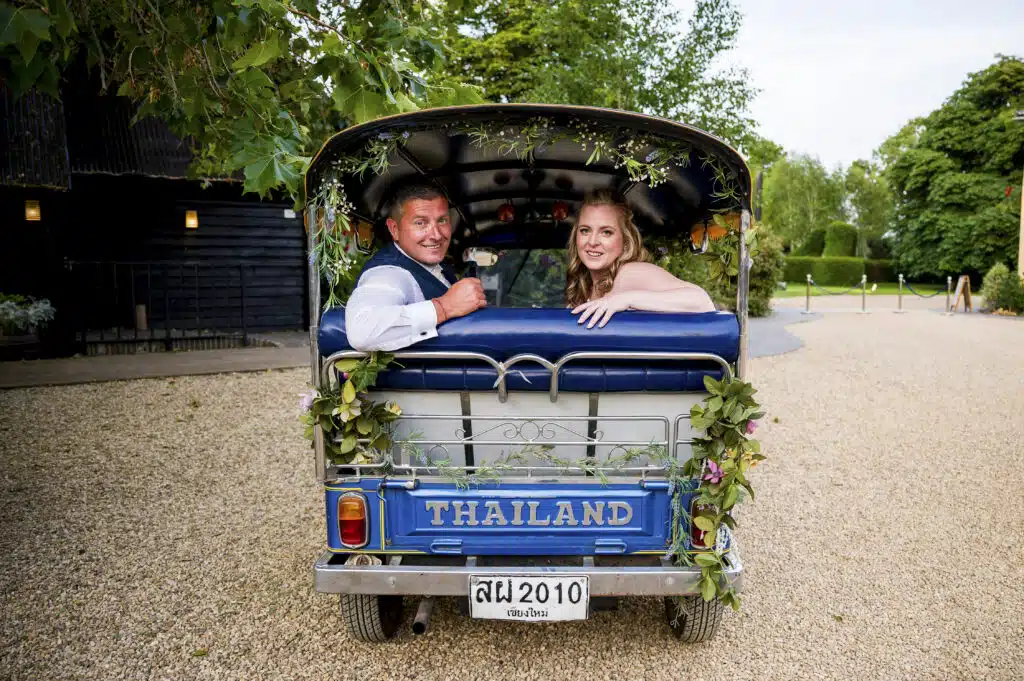 Couple in blue Thai Tub Tuk at countryside wedding venue 