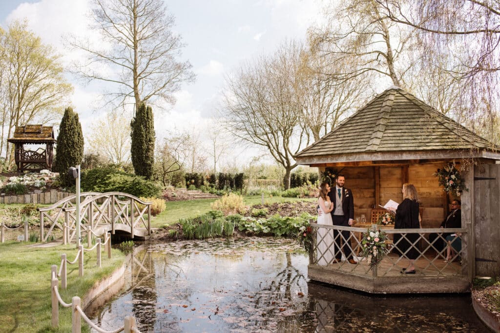 Outdoor wedding ceremony in pretty rustic garden summerhouse by pond