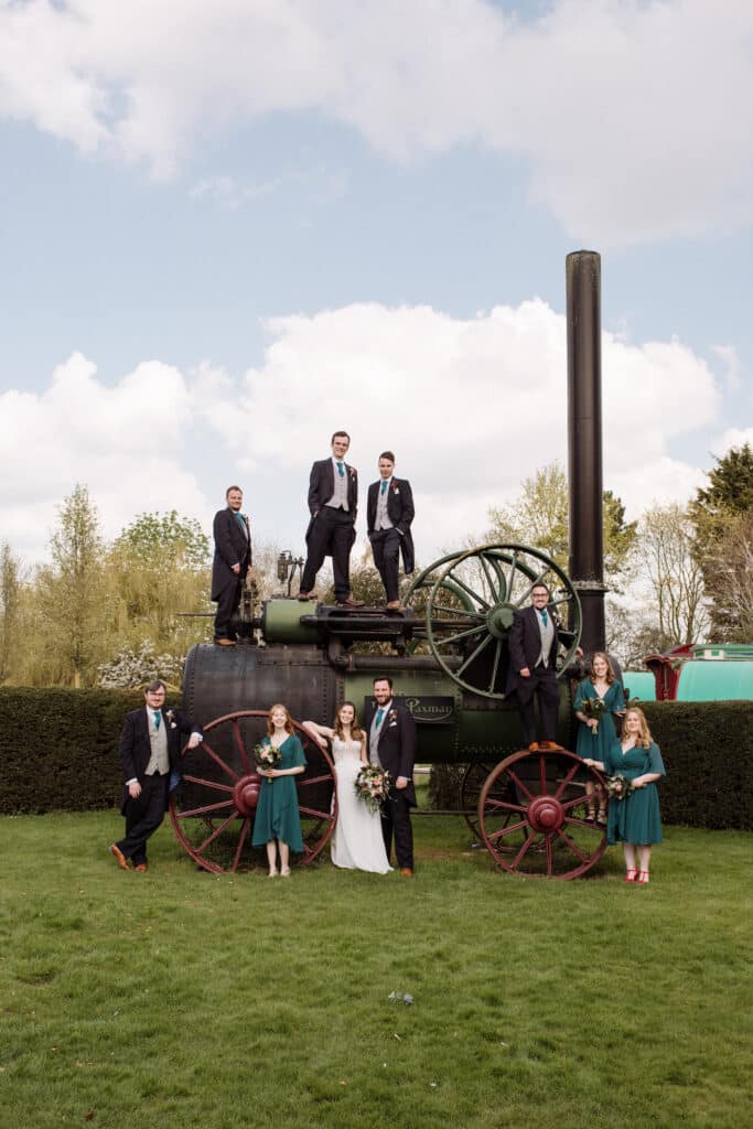Bride groom and wedding party at countryside wedding venue in front of rustic steam engine