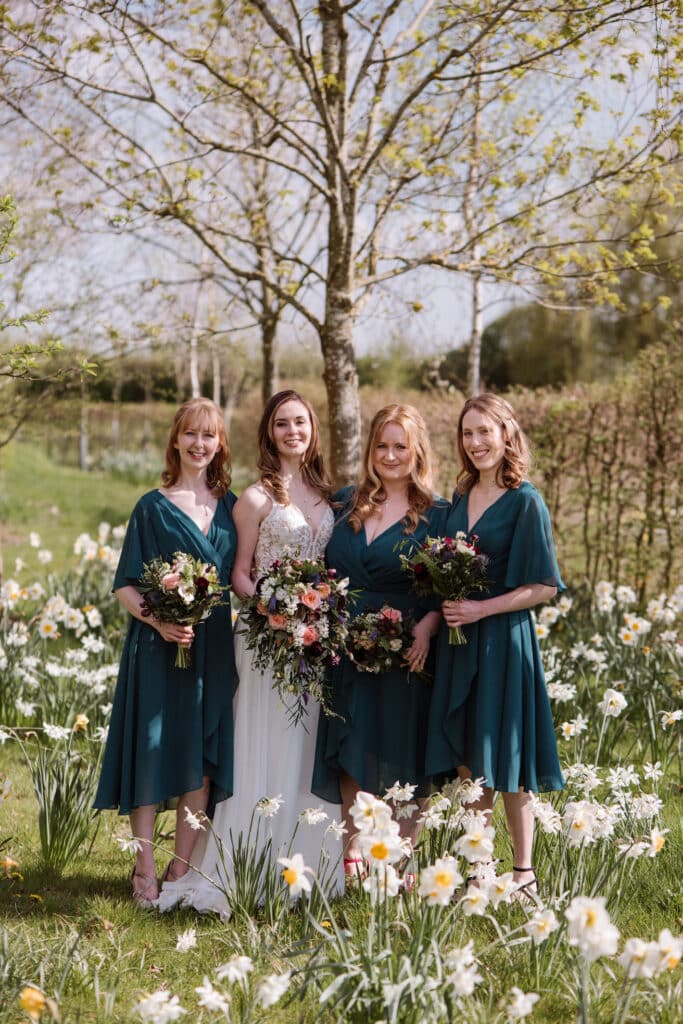 Bride and bridesmaids on wedding day in field full of daffodils