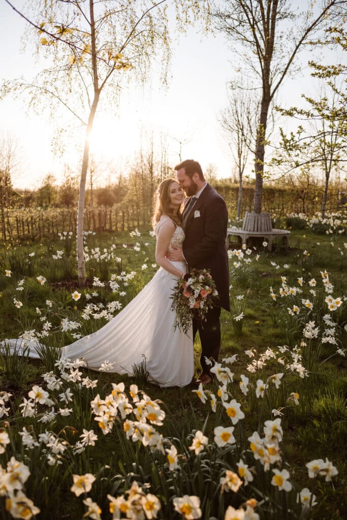 Bride and groom on wedding day in field of daffodils