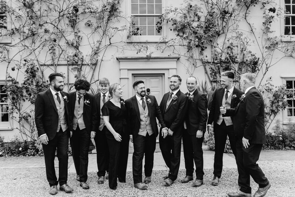 Black and white photo of groom and Groomsmen in front of country farm house