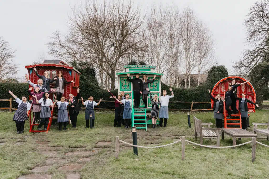 Staff at wedding venue in front of colourful Romany Wagons