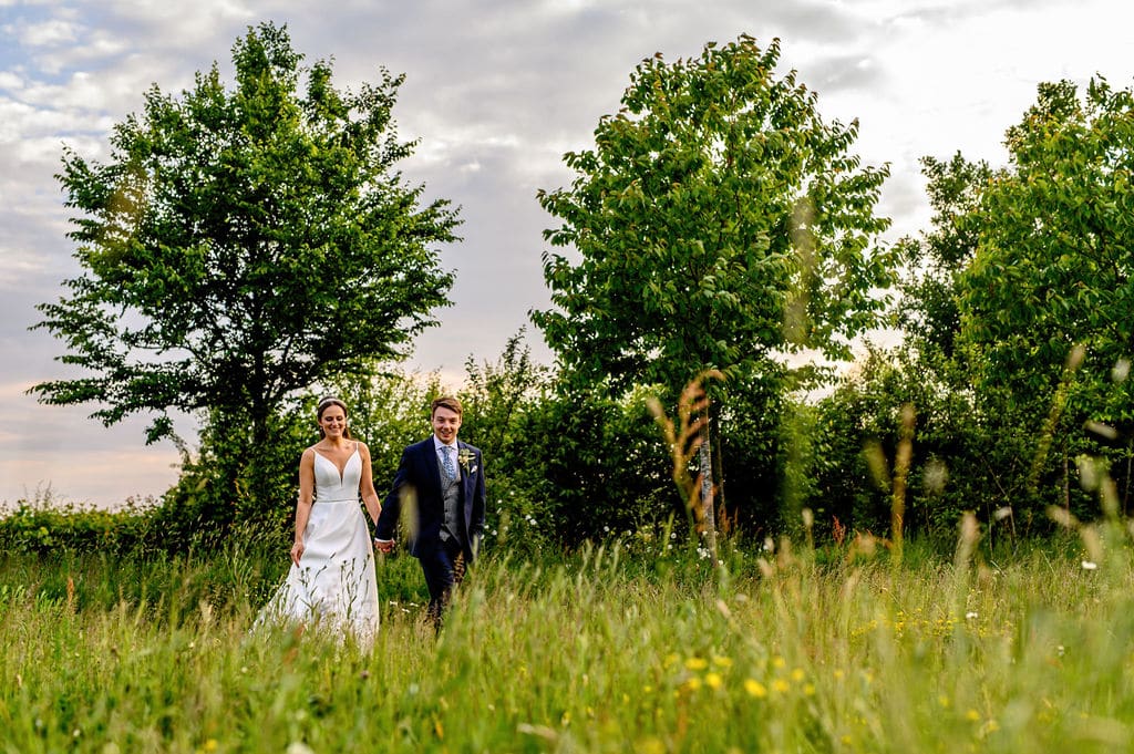 Bride and groom wander through rustic garden wedding venue on wedding day