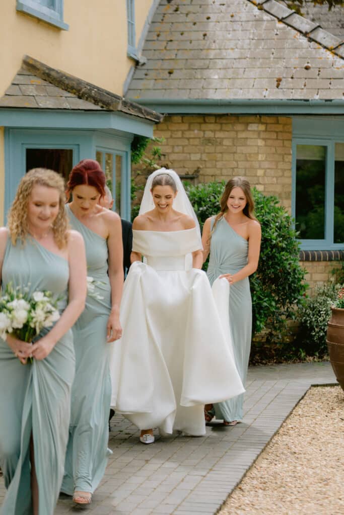 Bride and her bridesmaids walking out the bridal suite at charming rustic barn wedding venue