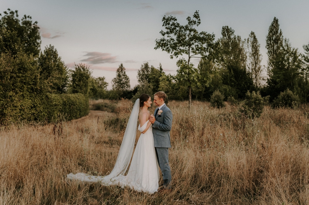 Bride and groom on sunny day in wild flower garden at outdoor wedding venue