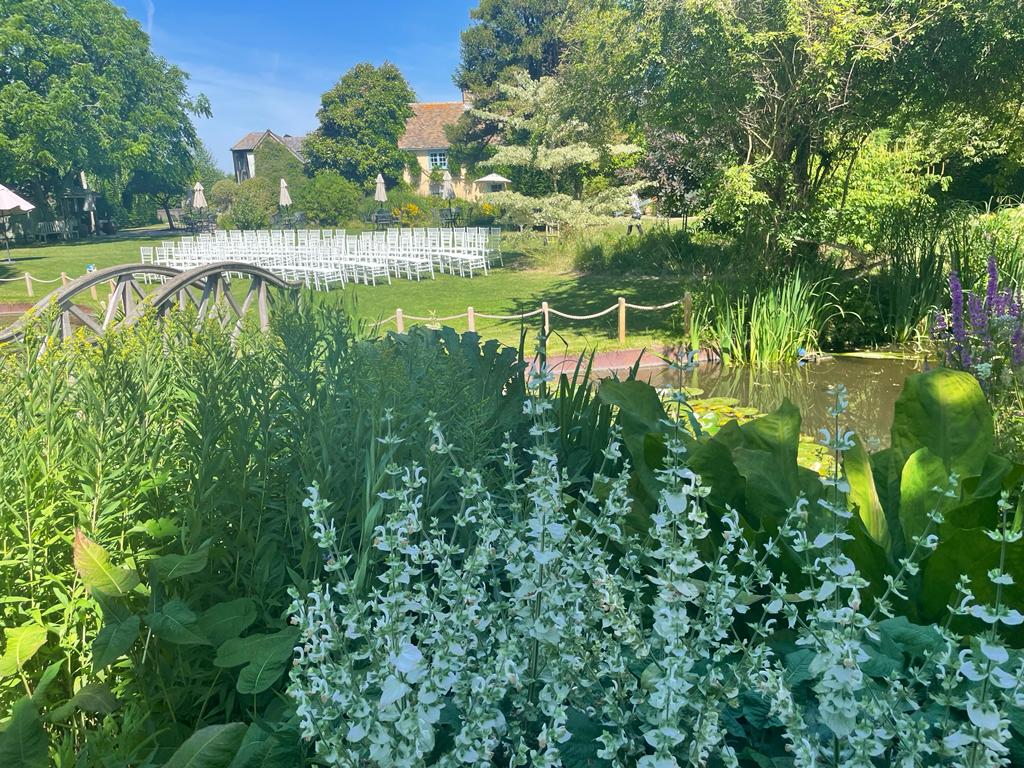 Beautiful July day at garden wedding venue with lawns set up with white chairs for ceremony and white flower in the foreground