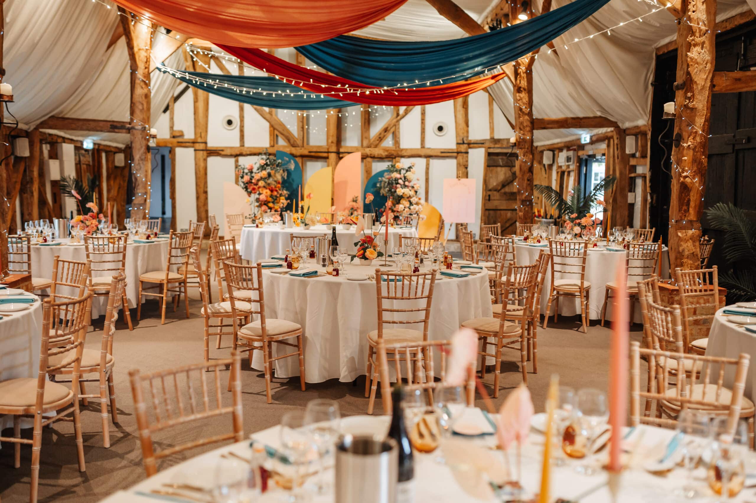 Stunning colourful decorations and candles in rustic barn set for wedding meal