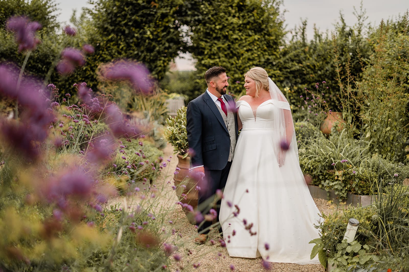 Bride and groom standing in pretty herb garden at farm wedding venue