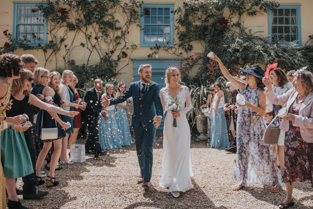Bride and Groom have confetti shower at farm house wedding venue