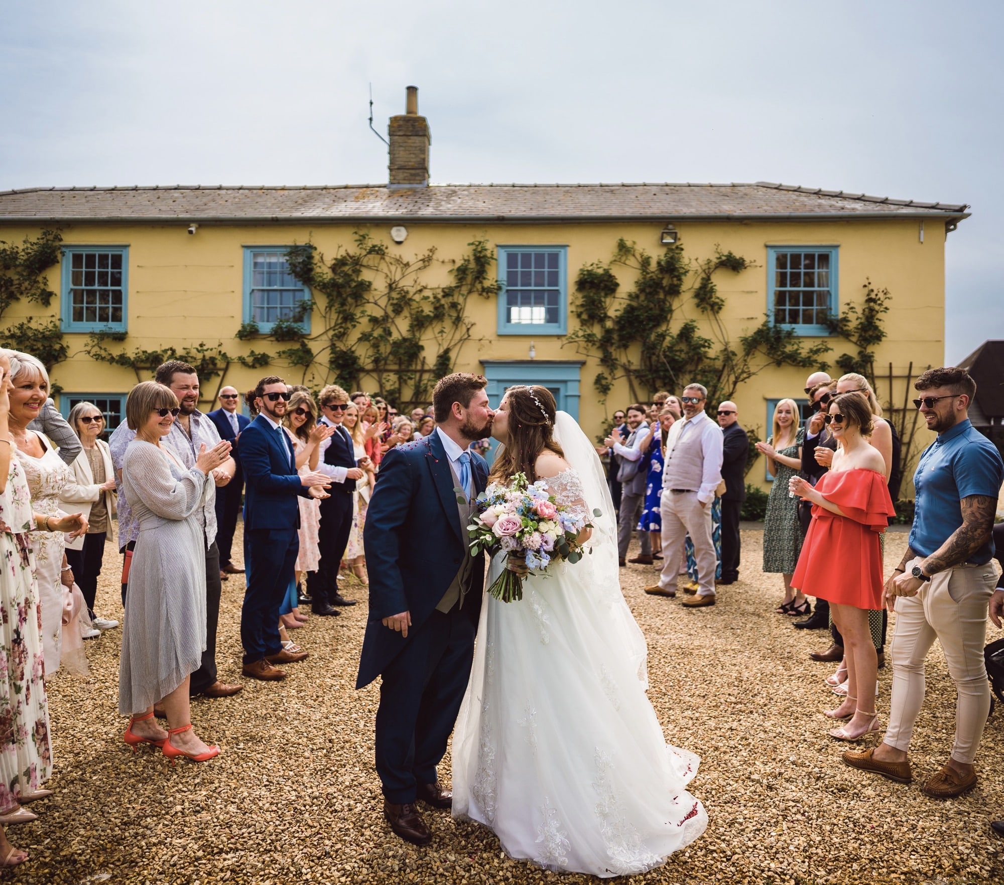 Bride and Groom kiss in front of country farm house wedding venue