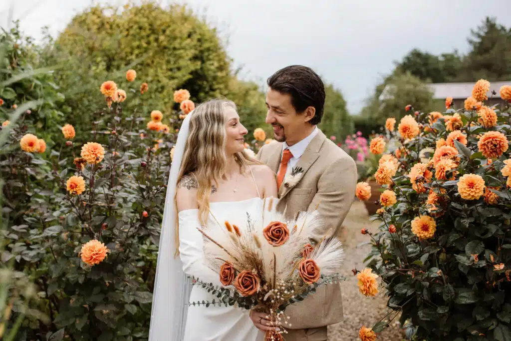 Just married couple on wedding day at countryside wedding venue surrounded by beautiful orange dahlias
