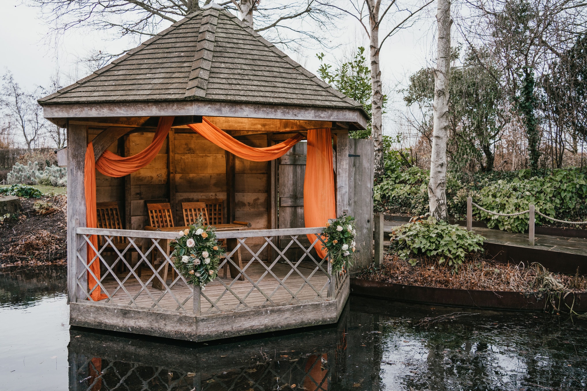 Pretty Garden Summerhouse decorated with orange swag and flowers at Wedding venue Open Day