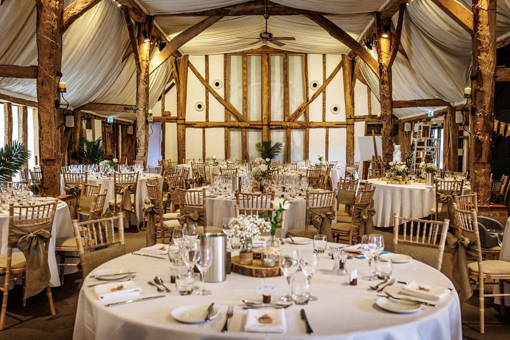 Barn wedding venue beautiful barn with honey coloured historic beams set with round tables ready for dining