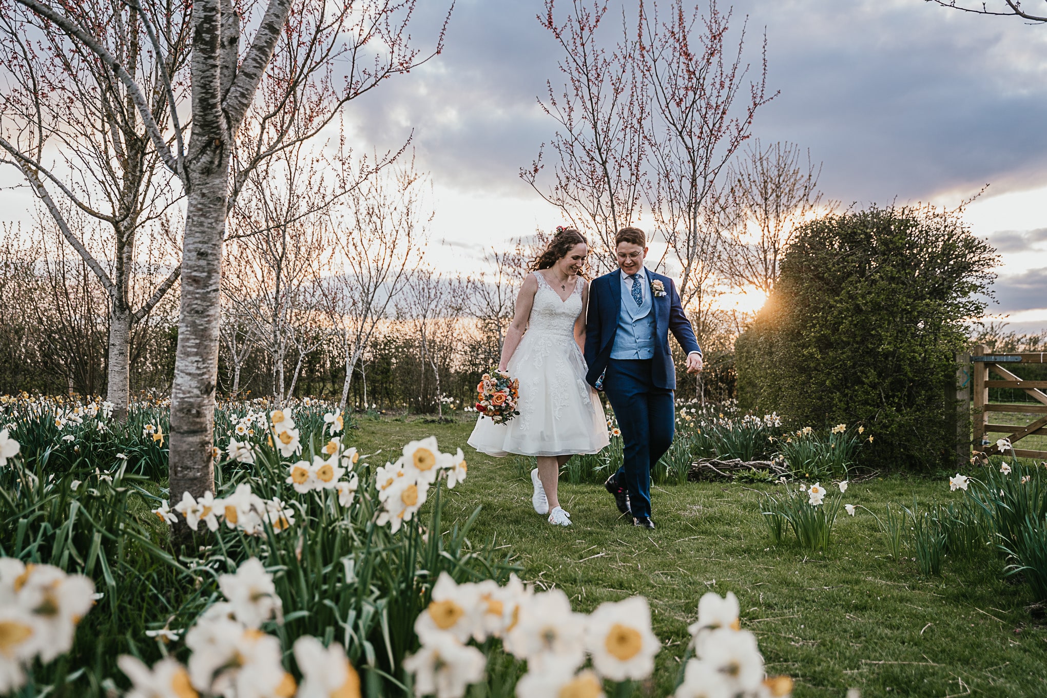Bride and groom in meadow of spring daffodils at countryside wedding venue