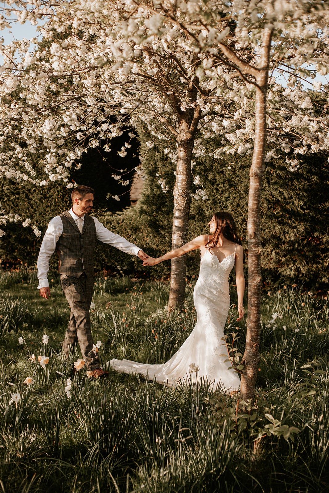 Bride and Groom taking a romantic stroll through the blossoms at wedding venue in Hertfordshire