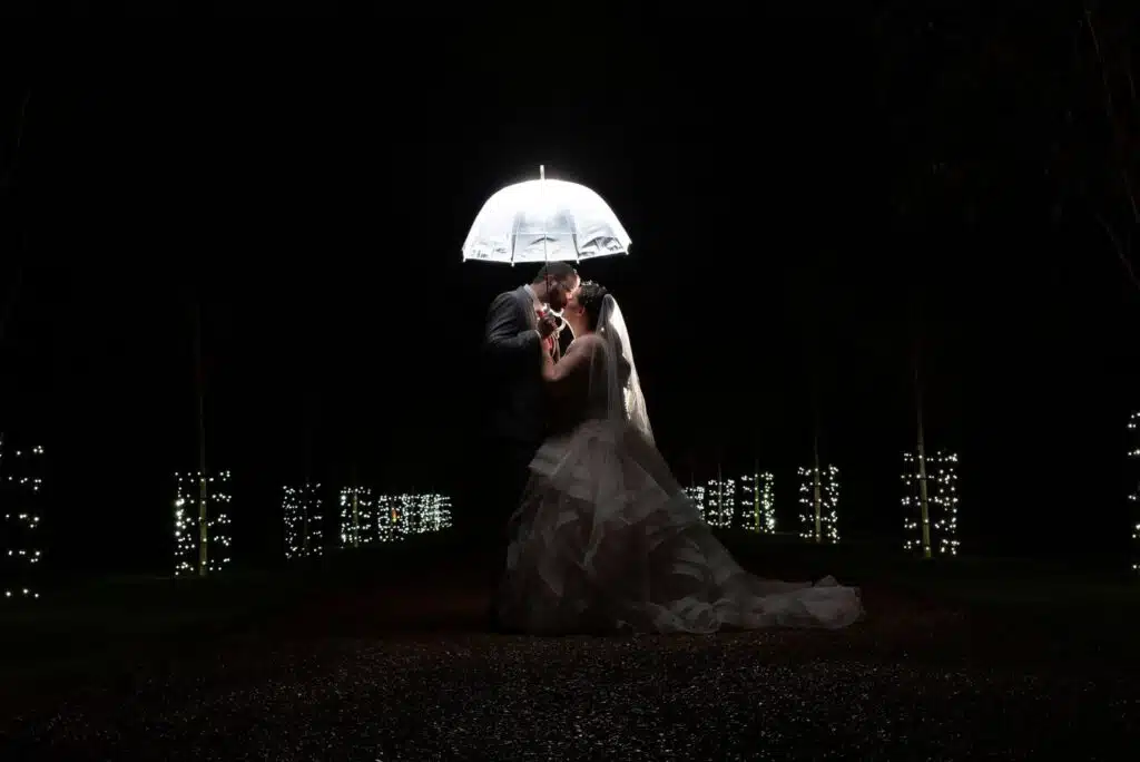 Bride and Groom kissing under umbrella at twilight down starlit driveway at South Farm