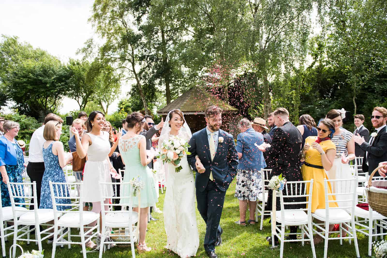 GARDEN WEDDING CEREMONY BRIDE AND GROOM WALK DOWN THE AISLE
