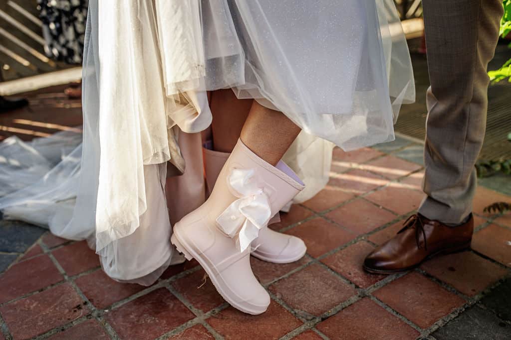 Bride wearing white wedding wellies with bow at farm wedding 