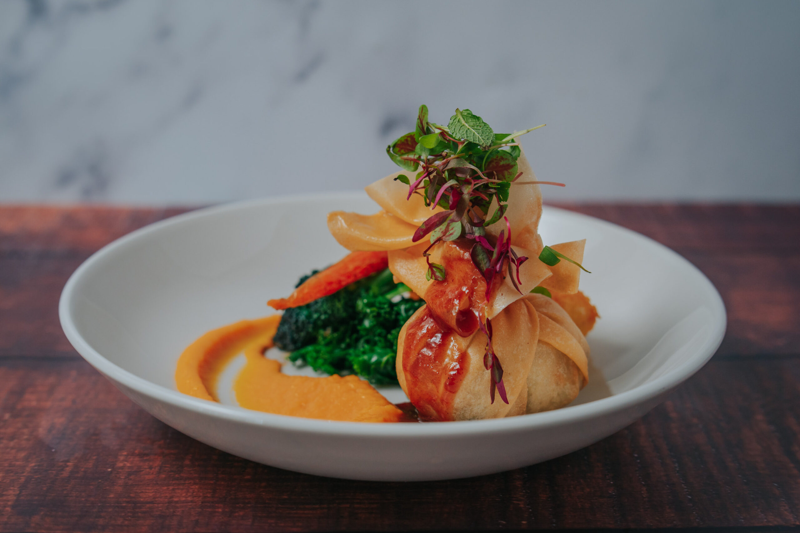 Delicious plated wedding main course at sustainable wedding venue plated on white plate is a Filo Parcel with carrots and chard