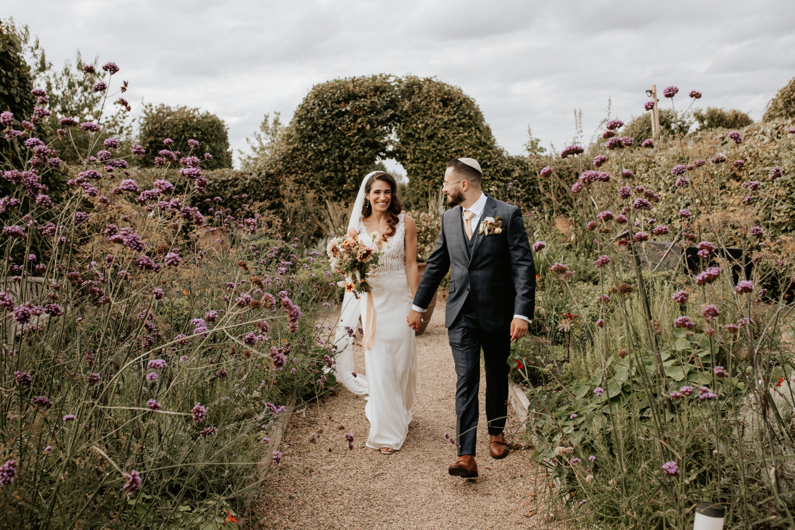 Jewish Wedding photo Bride and Groom wander through pretty herb garden hand in hand on wedding day