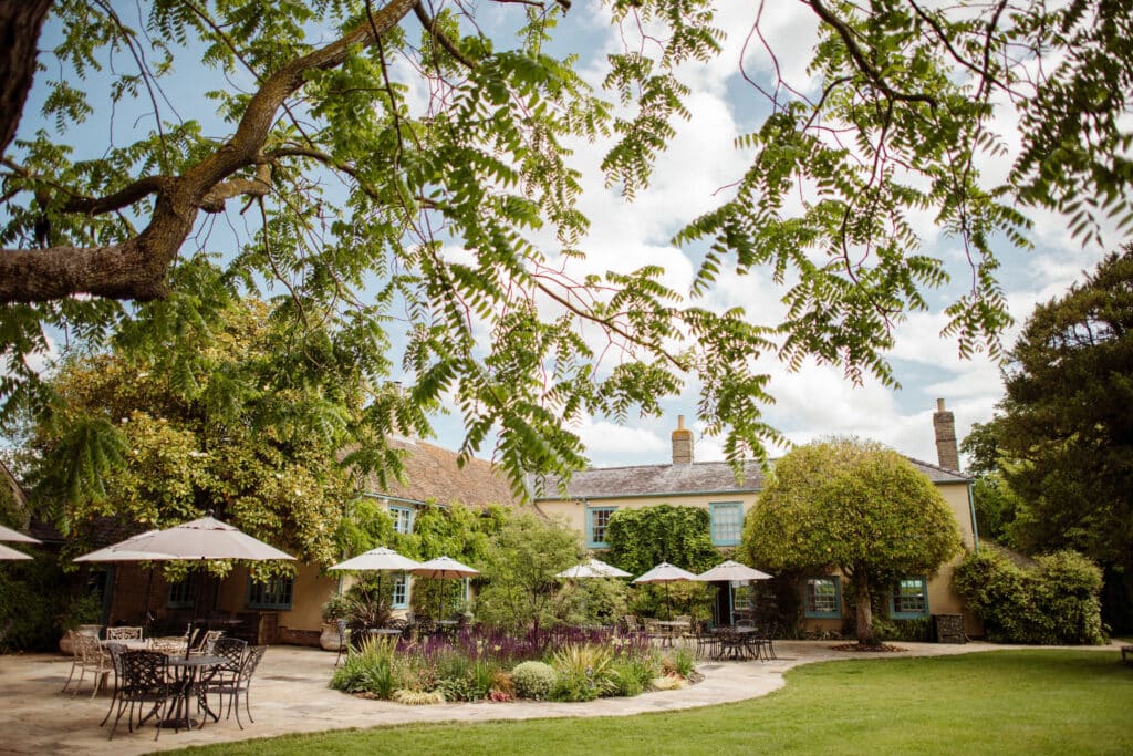 Stunning garden wedding venue set for wedding drinks reception with pretty parasols on sun terrace surround by gorgeous gardens