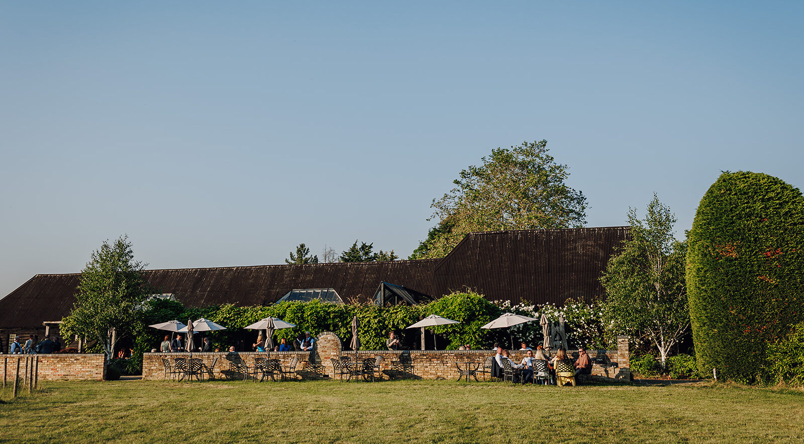Guest enjoy an early evening drink at country wedding venue Cambridge in outdoor grounds