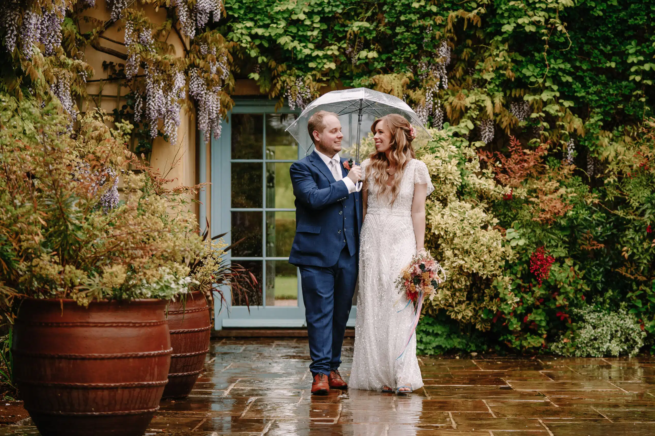 Bride and Groom standing on the Garden Terrace adorned with Wisteria
