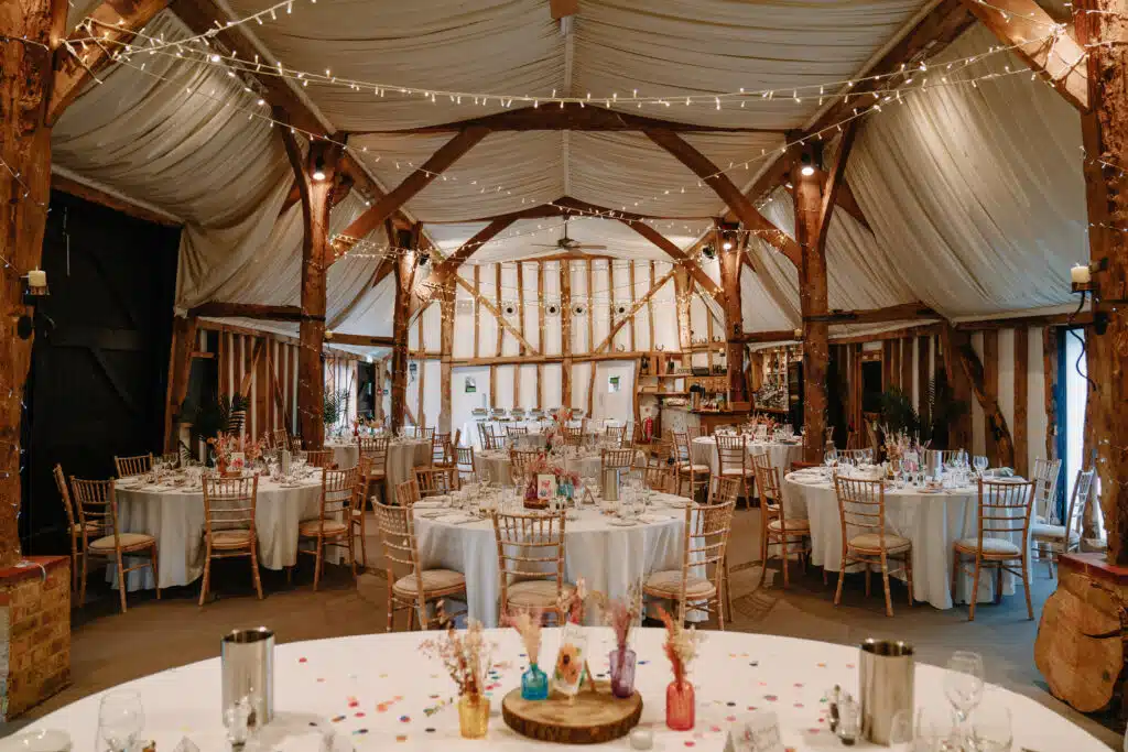 Beautiful barn set for wedding dinner with twinkly lights and pretty flowers