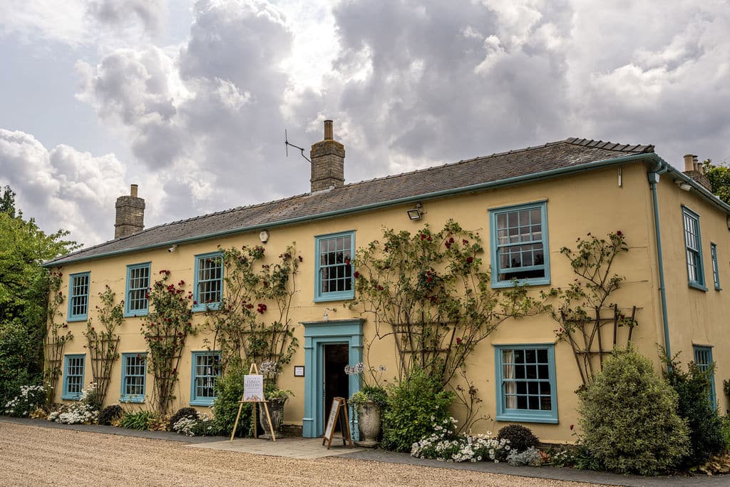 Countryhouse wedding venue cream country farm house with blue framed windows and doors under a pretty cloudy sky