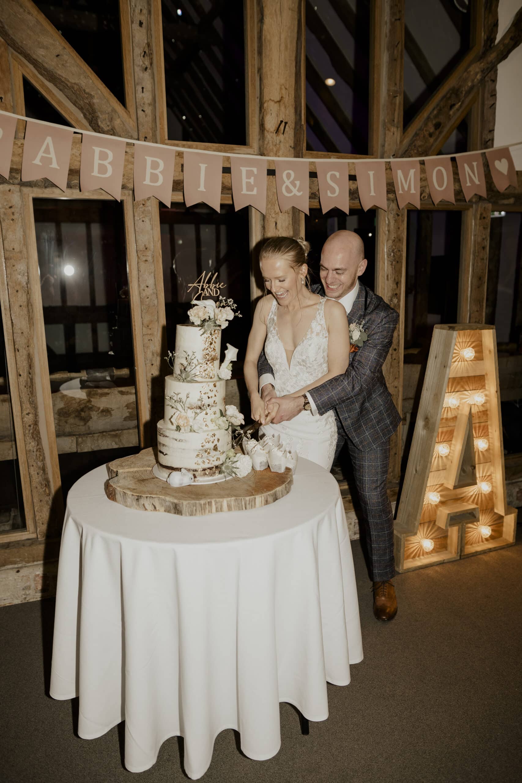 Bride and Groom ' Cutting the Cake' in the rustic Tudor Barn at barn wedding venue