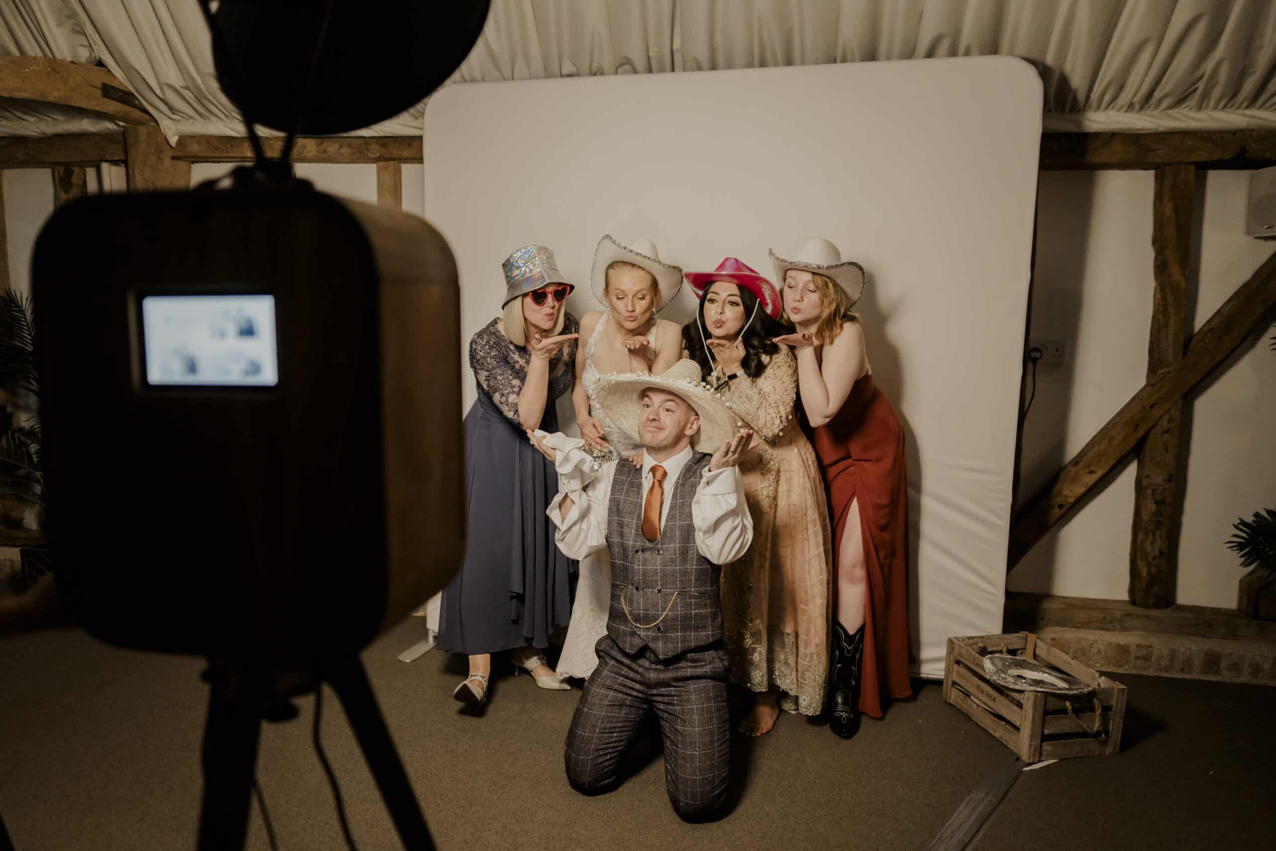 Say Cheese! Wedding guests having fun with photobooth props and cowboy hats in charming Tudor Barn at South Farm based near Hertfordshire