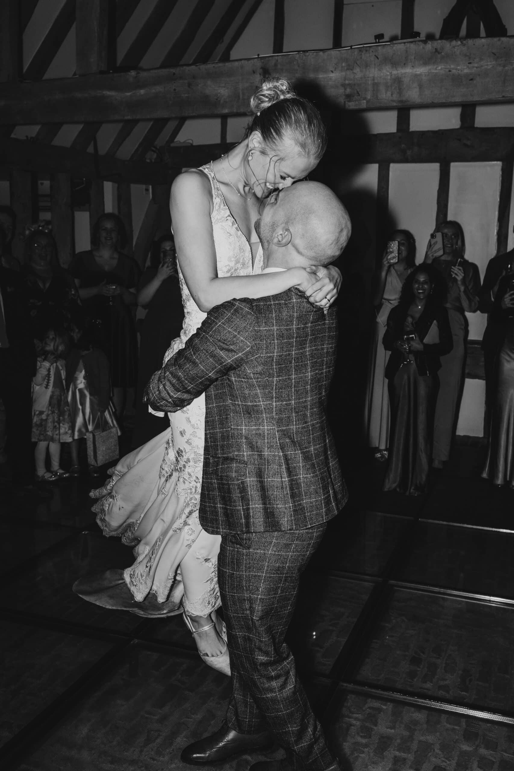 Groom picking up the Bride on the dance floor in The Horse Barn at barn wedding venue 