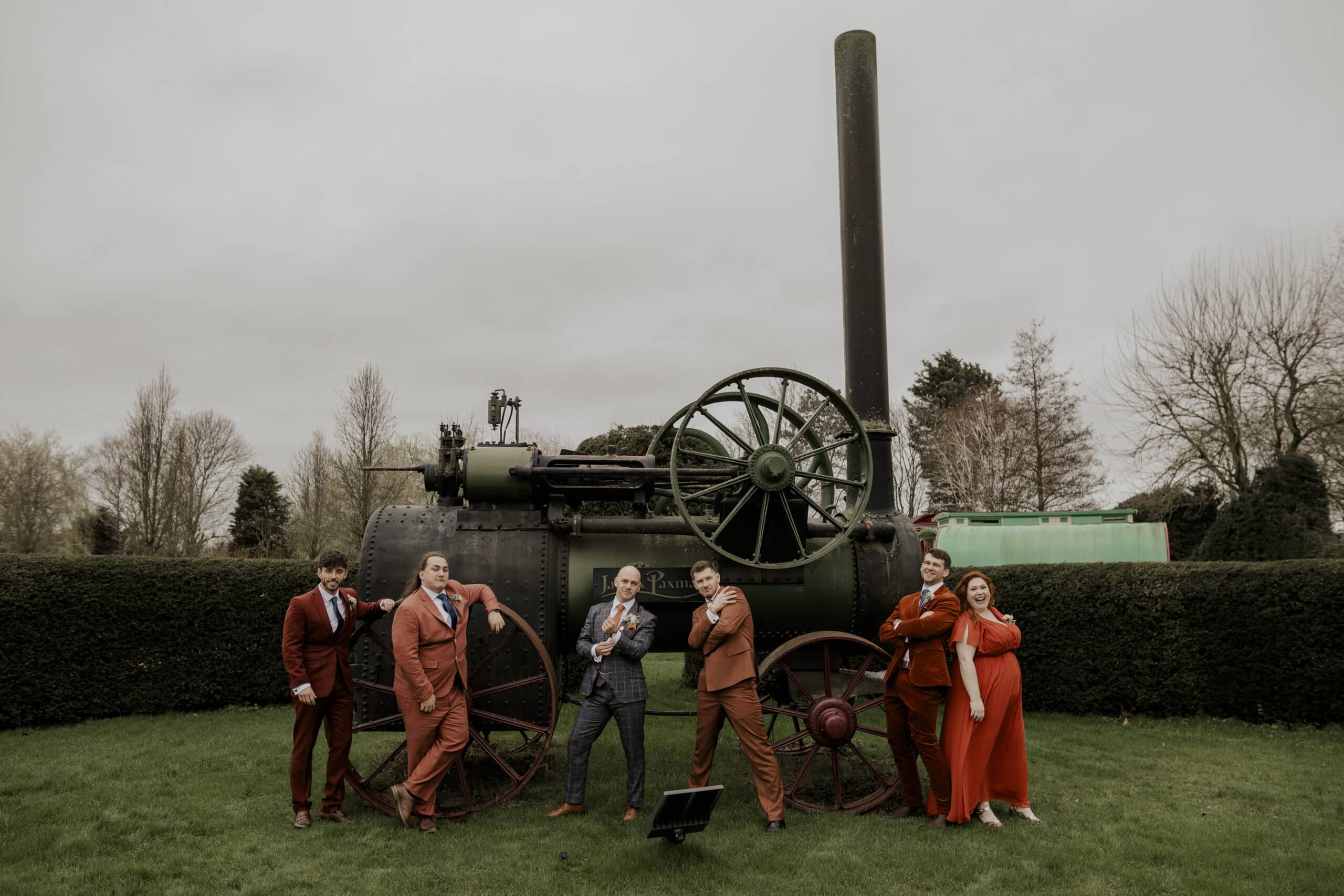 The Groom, Groomsmen and Best Women posing at the front of South farm's Steam Engine at outdoor garden ceremony near Bedfordshire