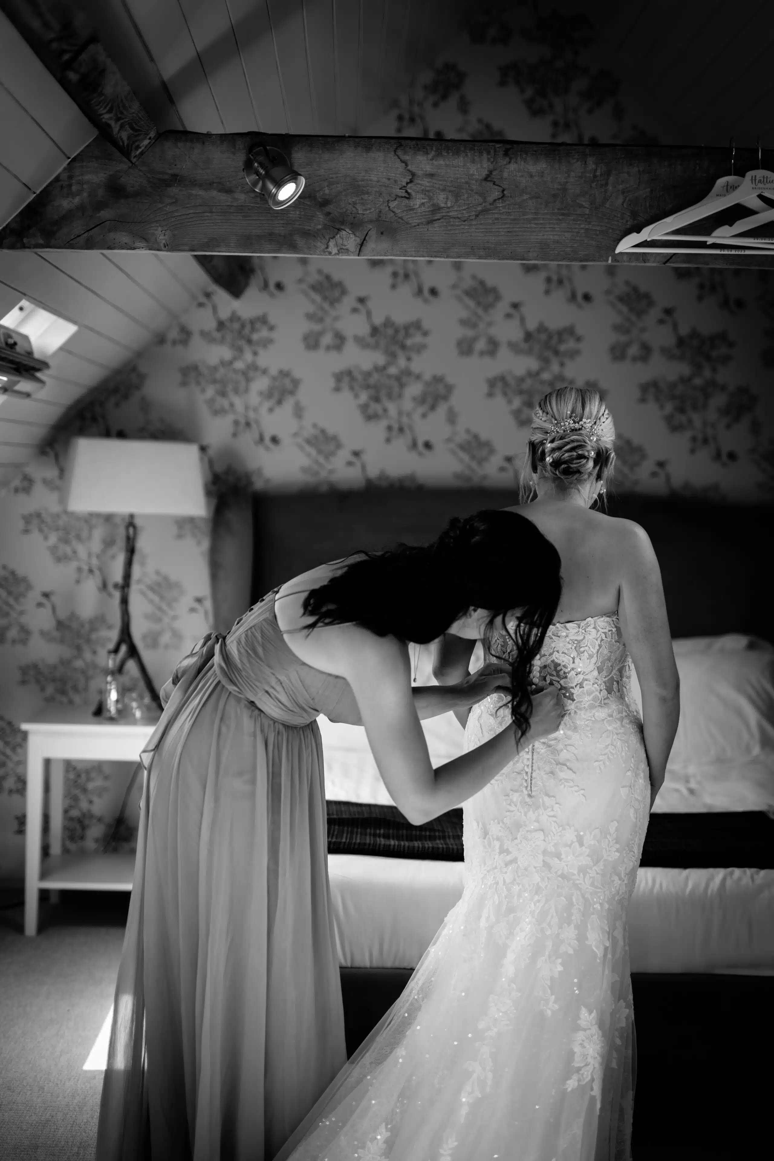 Bride having her dress buttoned in the Coach House Suite at outdoor garden wedding venue